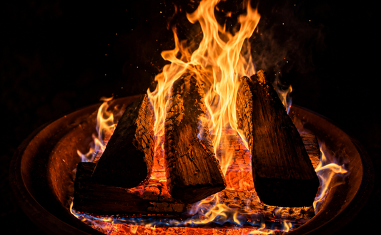 Burning firewood glowing with bright flames and embers in a fire pit at night, illustrating the release of stored energy and light.